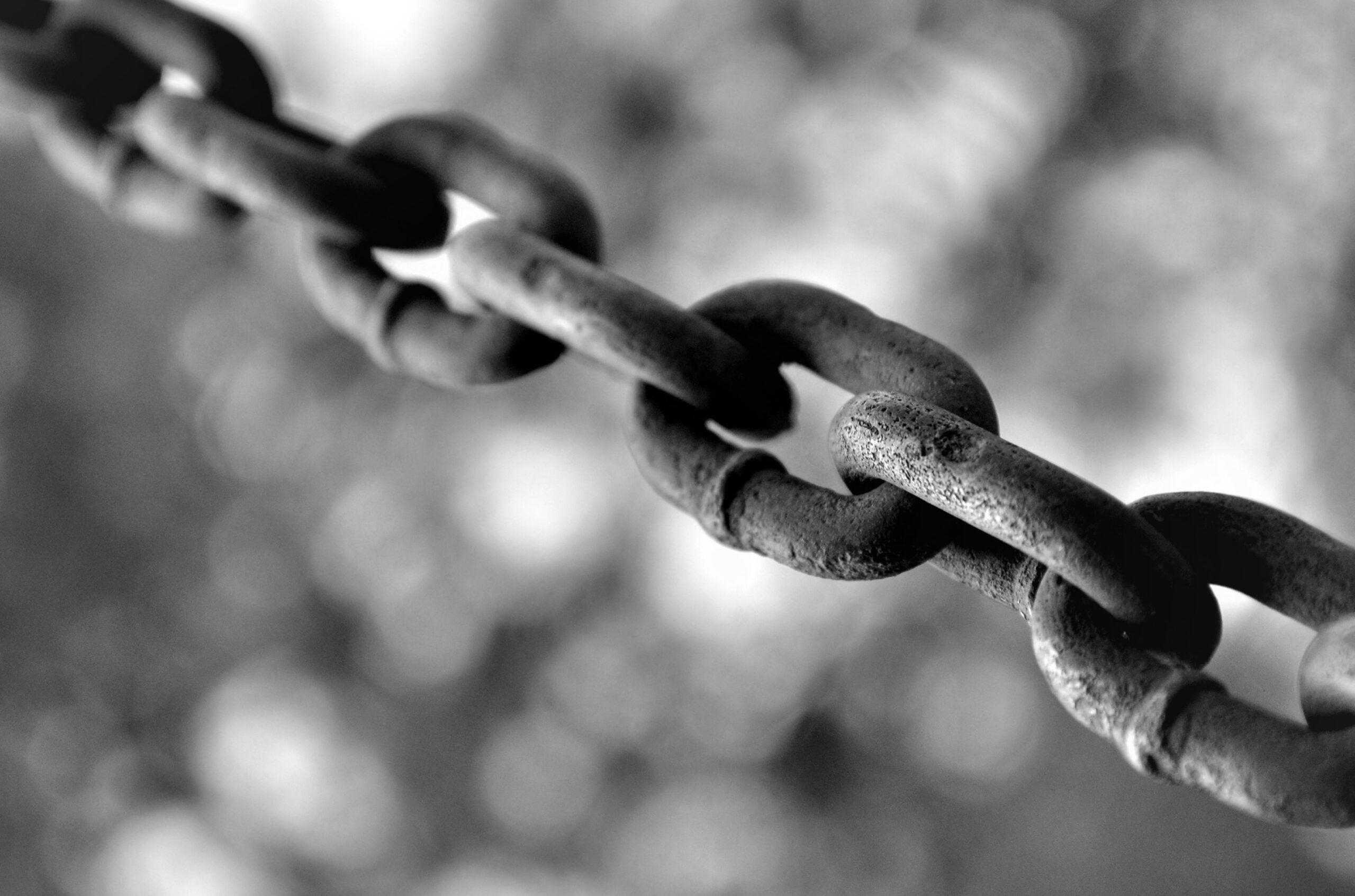 a close of a metal chain with a blurry background in black and white.