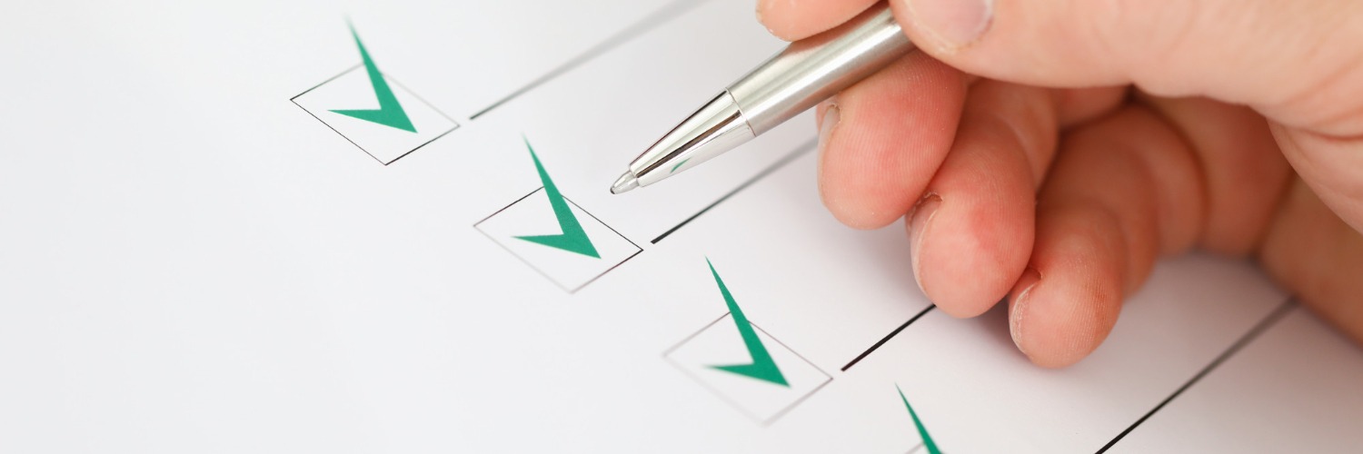 A hand writing on a checklist with green checkmarks . 