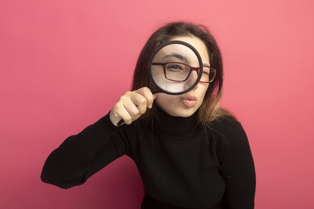 Young woman holding a magnifying glass up to her eye
